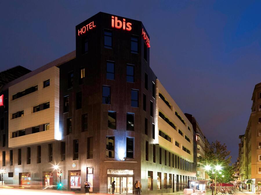 Un hotel moderno con un llamativo letrero de "ibis", varios pisos y una entrada a nivel de calle.