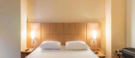 Una habitación de hotel con una cama grande, dos mesitas de noche y un cabecero de madera.