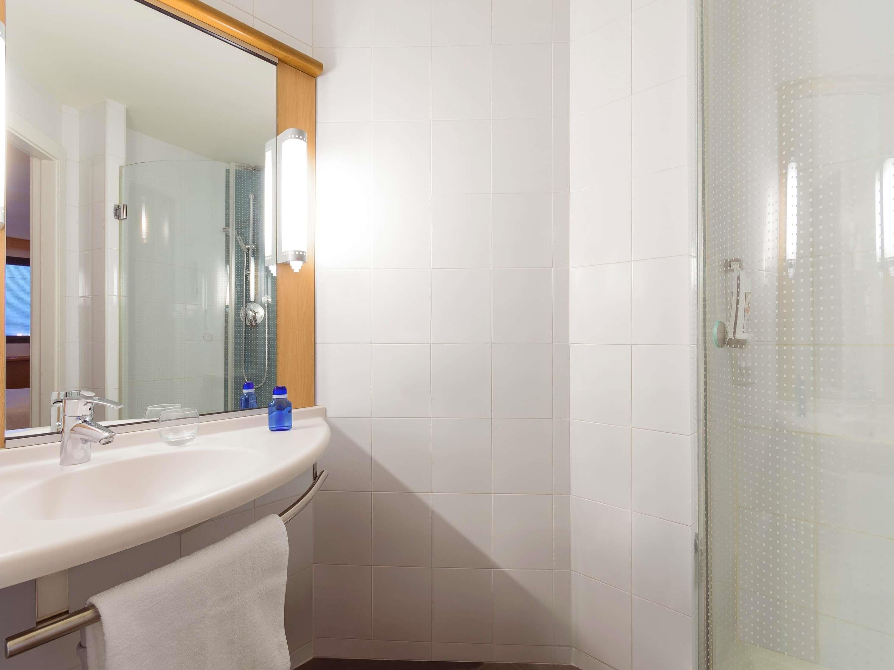 A modern bathroom with a white sink, a mirror, and a glass shower enclosure.