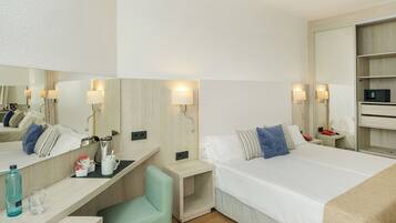 Ein modernes Hotelzimmer mit Bett, Nachttischen, Schreibtisch, Stuhl, Spiegel und Kleiderschrank.