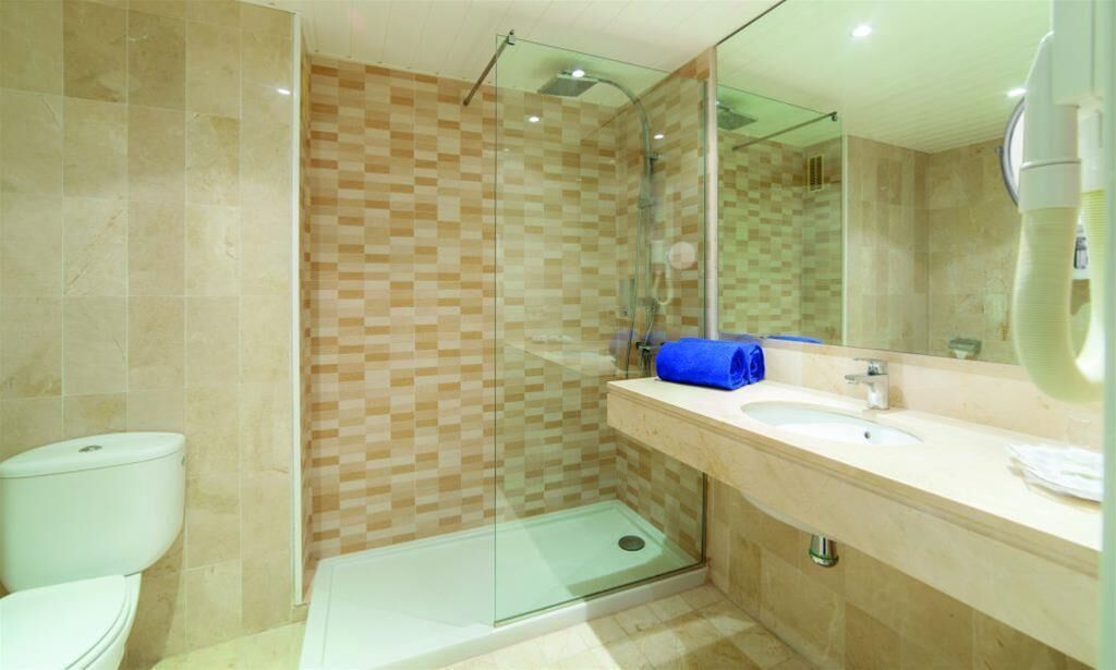 Ein modernes Badezimmer mit einer Duschkabine aus Glas, einem Waschbecken mit Spiegel und einer Toilette.