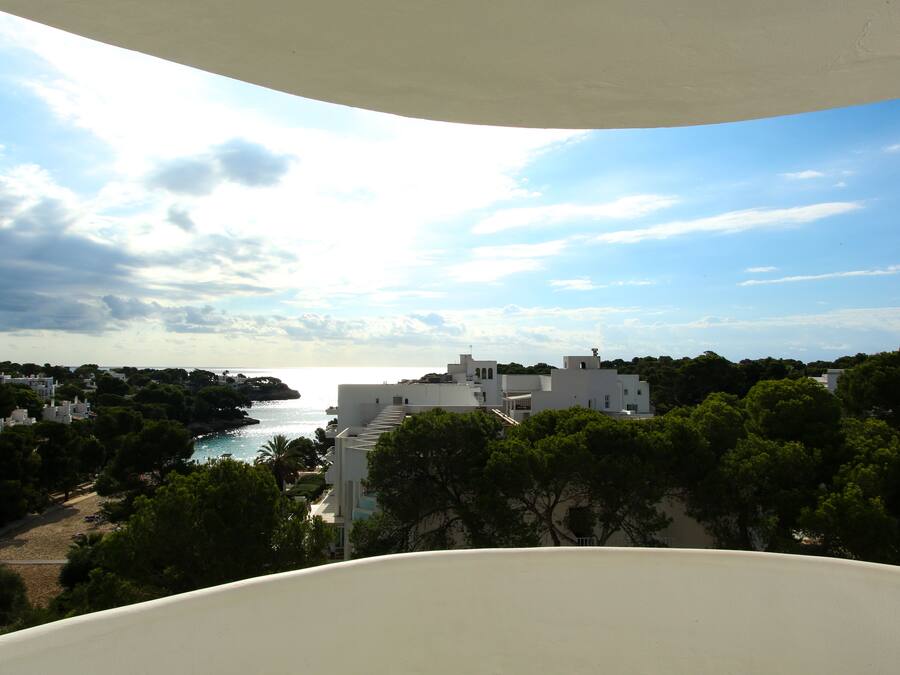 A coastal view with buildings, trees, and a beach.