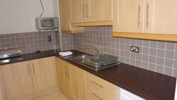 A kitchen with wooden cabinets, a microwave, a sink, and a dishwasher.