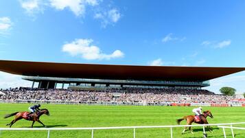 Una pista de carreras de caballos con un estadio moderno grande y una multitud de espectadores.