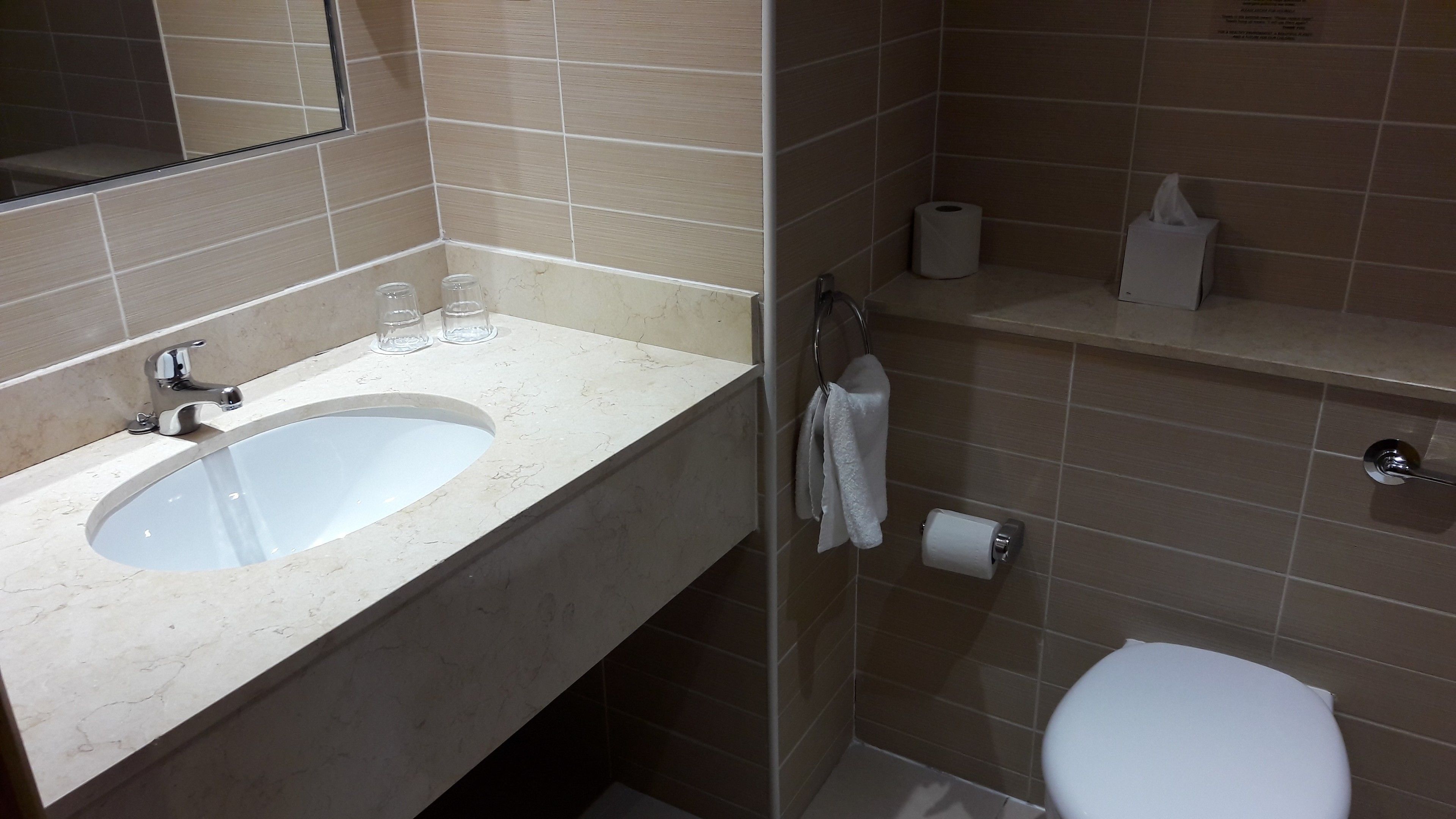 A bathroom with a sink, mirror, toilet, and towel rack.