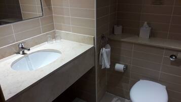 A bathroom with a sink, mirror, toilet, and towel rack.