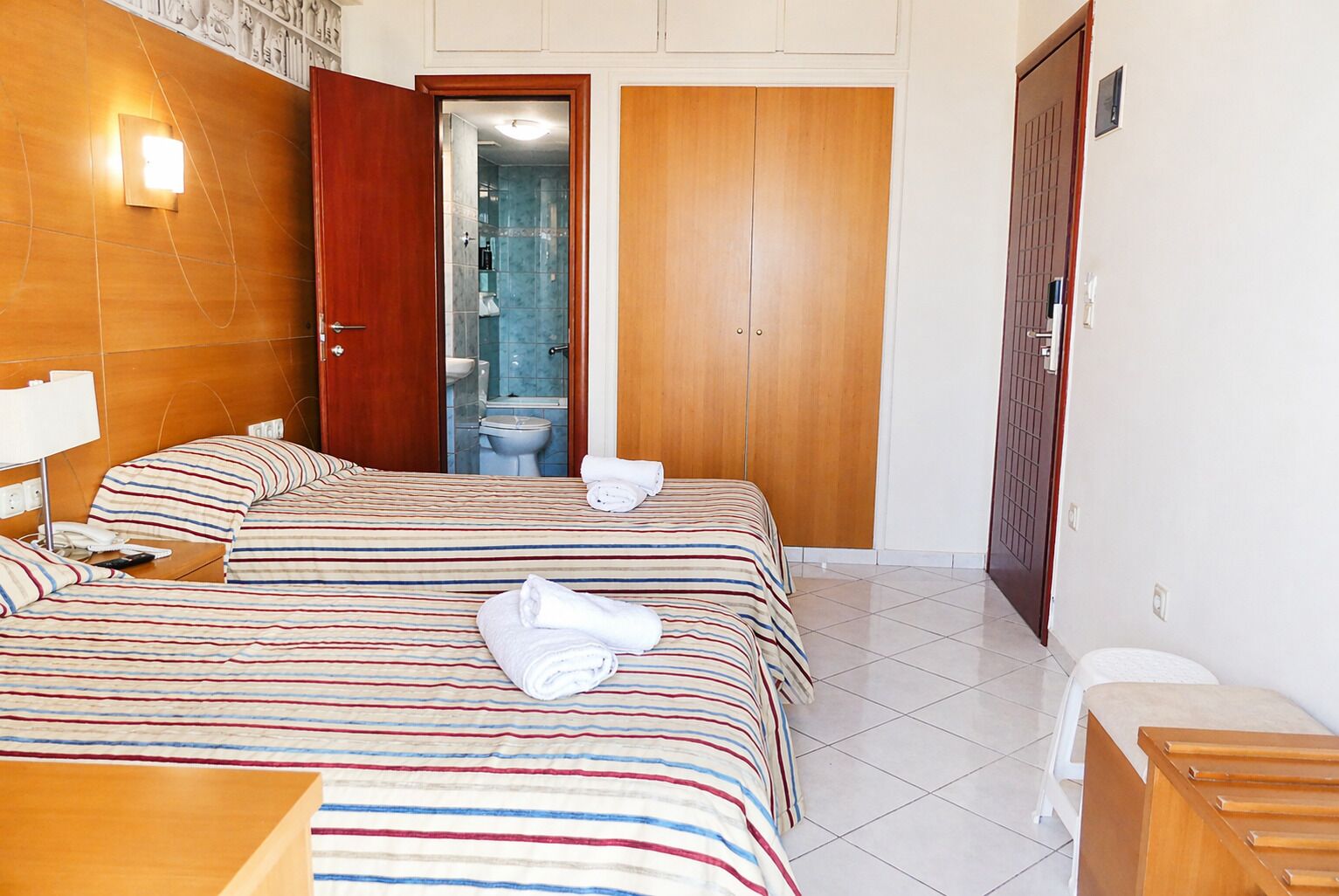 Ein Hotelzimmer mit zwei Betten, einem Badezimmer und einem Kleiderschrank.