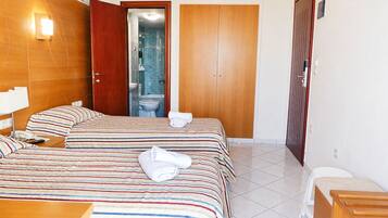 Ein Hotelzimmer mit zwei Betten, einem Badezimmer und einem Kleiderschrank.