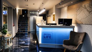 A hotel lobby with a reception desk, a staircase, and a wall-mounted map. - City Life Port Hotel (Heraklion)