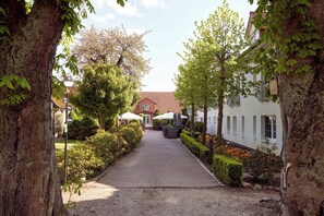 A pathway leading to a building with a red roof, surrounded by trees and shrubs. - Van der Valk Golfhotel Serrahn (Kuchelmiss)
