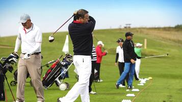 Un campo de golf con jugadores en movimiento, bolsas de golf y palos.