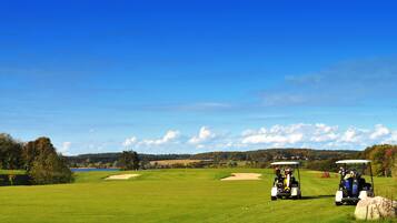 Een golfbaan met twee golfkarren en een heldere blauwe lucht.