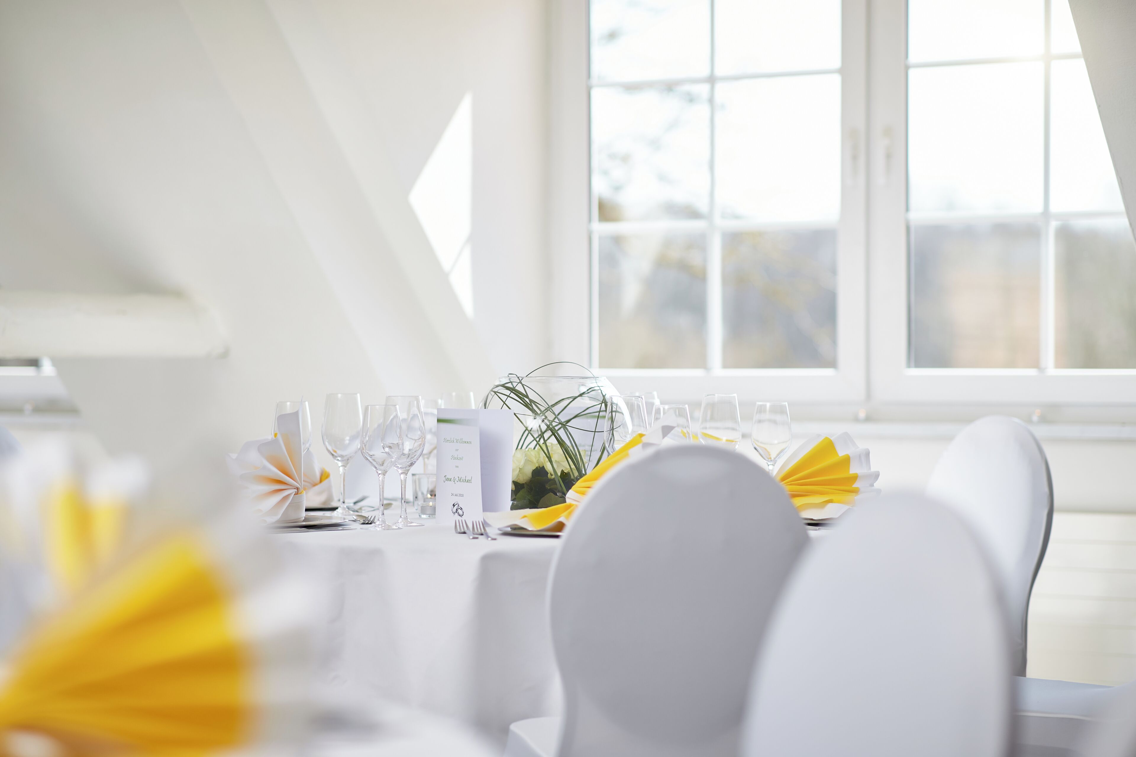 Et spisebord med hvide stole, en menu og en blomstervase.