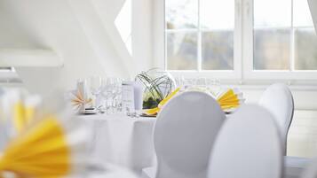 Et spisebord med hvide stole, en menu og en blomstervase.