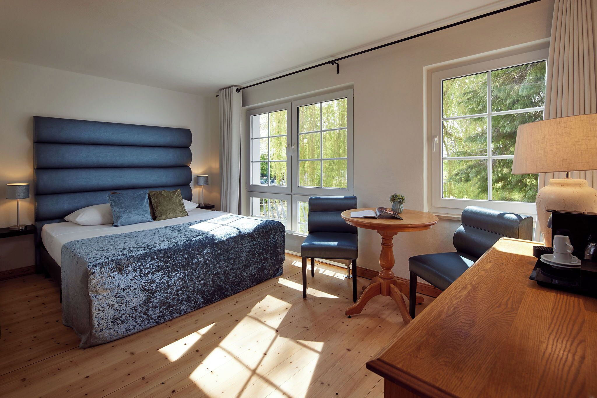 Ein Schlafzimmer mit Bett, Sessel, Tisch und Fenster.