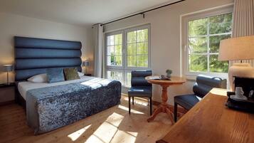 Ein Schlafzimmer mit Bett, Sessel, Tisch und Fenster.