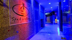 Un couloir avec une enseigne indiquant « Spa et bien-être » et un logo représentant une femme dans une posture de yoga.
