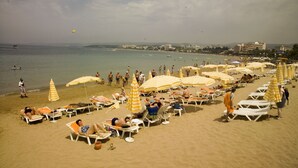 Une plage avec des transats et des parasols, un ciel dégagé et une mer calme.