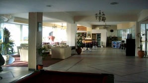 A spacious living area with a dining table, chairs, and a sofa. There is a kitchen area in the background with a refrigerator and a microwave. - San Remo Resort Hotel (Santa Teresita)