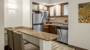 A compact kitchen with granite countertops, stainless steel appliances, and wooden cabinets. - Staybridge Suites Chattanooga at Hamilton Place by IHG (Chattanooga)
