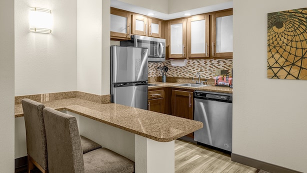 A compact kitchen with granite countertops, stainless steel appliances, and wooden cabinets. - Staybridge Suites Chattanooga at Hamilton Place by IHG (Chattanooga)
