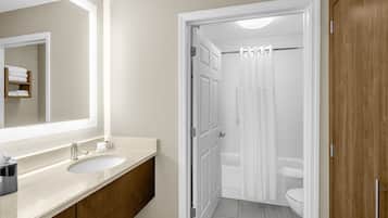 Baño con lavamanos doble, espejo y zona de ducha.