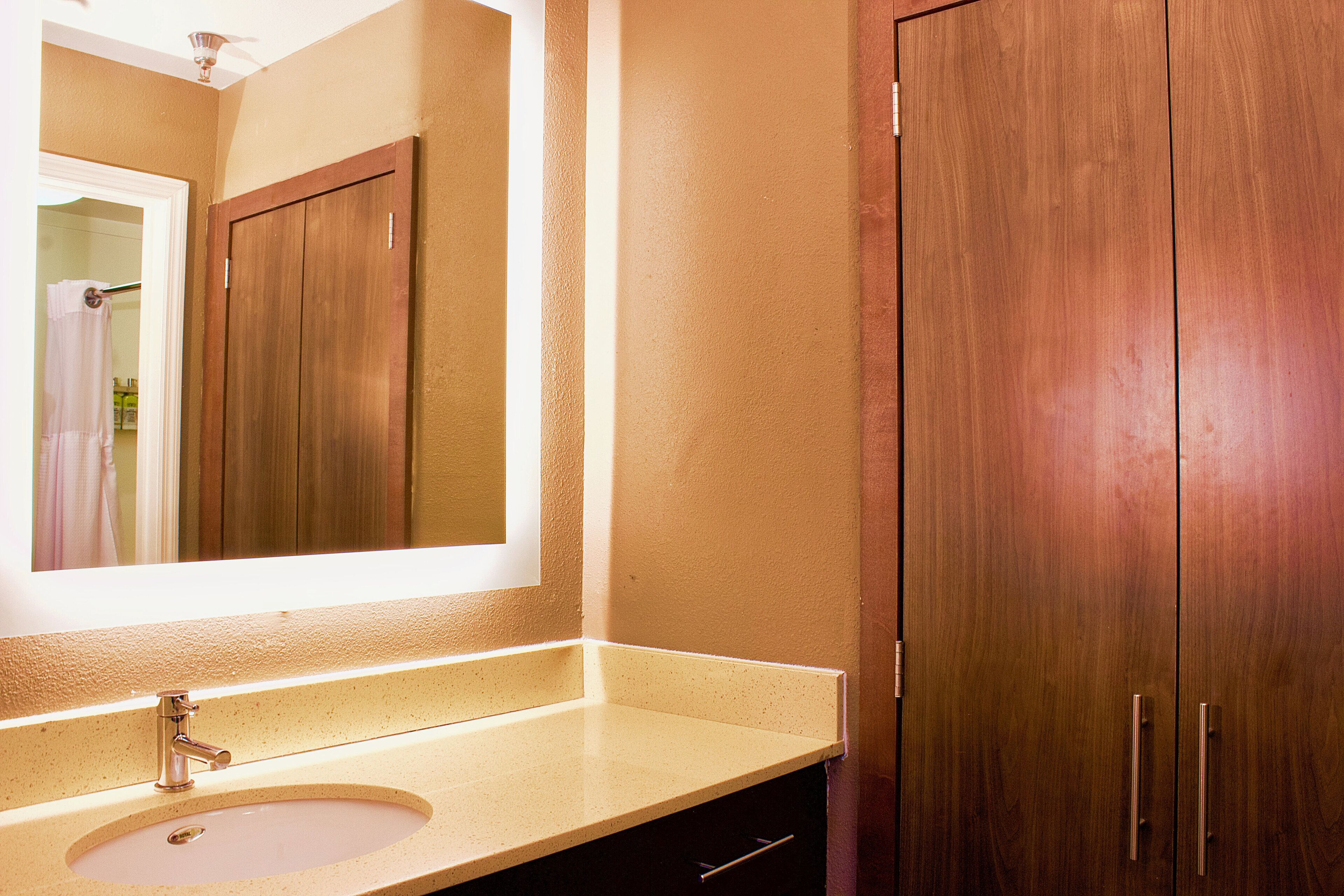 A bathroom with a sink, mirror, and wooden cabinets.