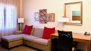 A hotel room with a sofa, a desk, a chair, two lamps, and artwork on the wall. - Staybridge Suites Chattanooga at Hamilton Place by IHG (Chattanooga)