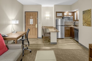 Habitación de hotel compacta con kitchenette, comedor y zona de estar.