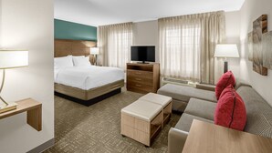 A hotel room with a bed, a TV, a desk, a sofa, and a window with curtains. - Staybridge Suites Chattanooga at Hamilton Place by IHG (Chattanooga)