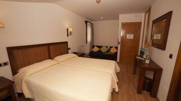 Habitación de hotel con cama doble, mesitas de noche, un espejo y una pequeña mesa con un florero.