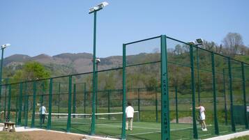 Ein Tennisplatz mit grünem Zaun, Netz und zwei spielenden Personen.