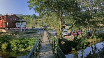 A riverside hotel with a bridge, outdoor seating, and a view of the river.