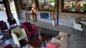Un rincón de descanso acogedor con una variedad de sillones y sofás, una mesa de centro de madera y una televisión montada en la pared.