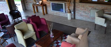 Un rincón de descanso acogedor con una variedad de sillones y sofás, una mesa de centro de madera y una televisión montada en la pared.