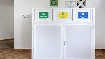 A recycling station with labeled bins for glass, plastic, and paper.