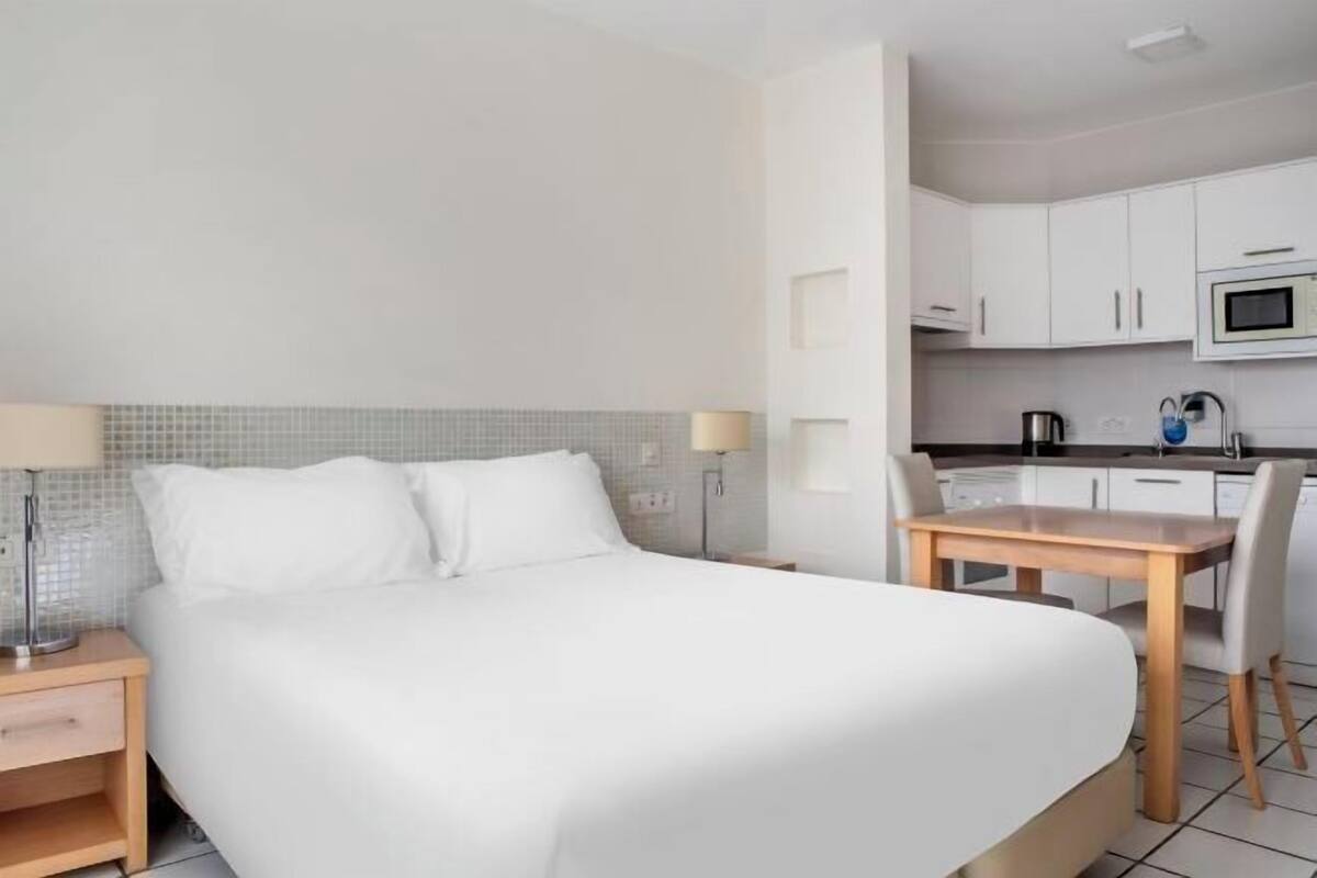 Ein Hotelzimmer mit Bett, Nachttischen, Schreibtisch, Stühlen, einer Mikrowelle und einem Wasserkocher.