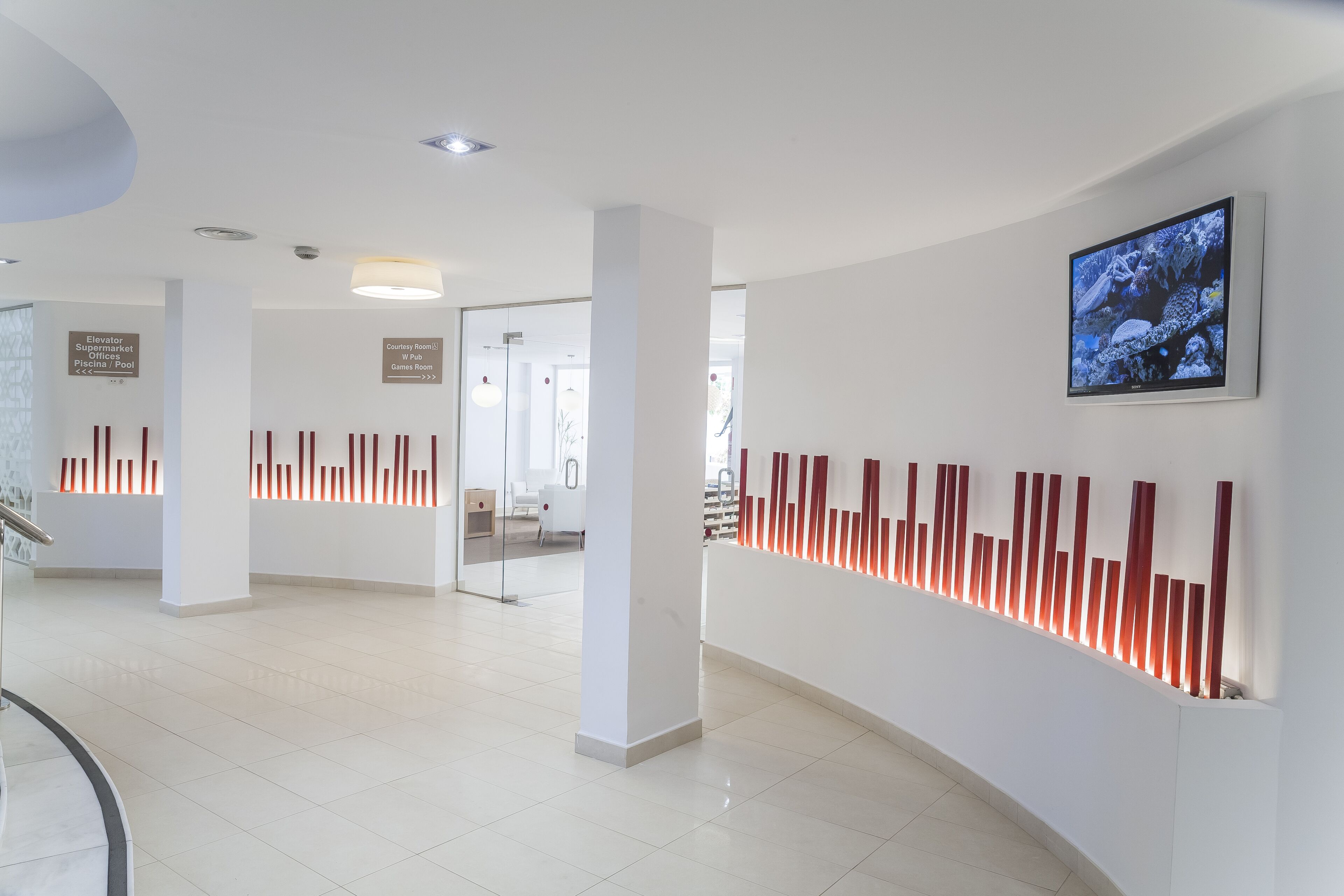 A modern interior with a curved wall, red vertical light fixtures, and a framed picture.