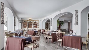 Un vaste espace dédié à la salle à manger, avec de nombreuses tables et chaises, des murs blancs et des œuvres d’art décoratives.