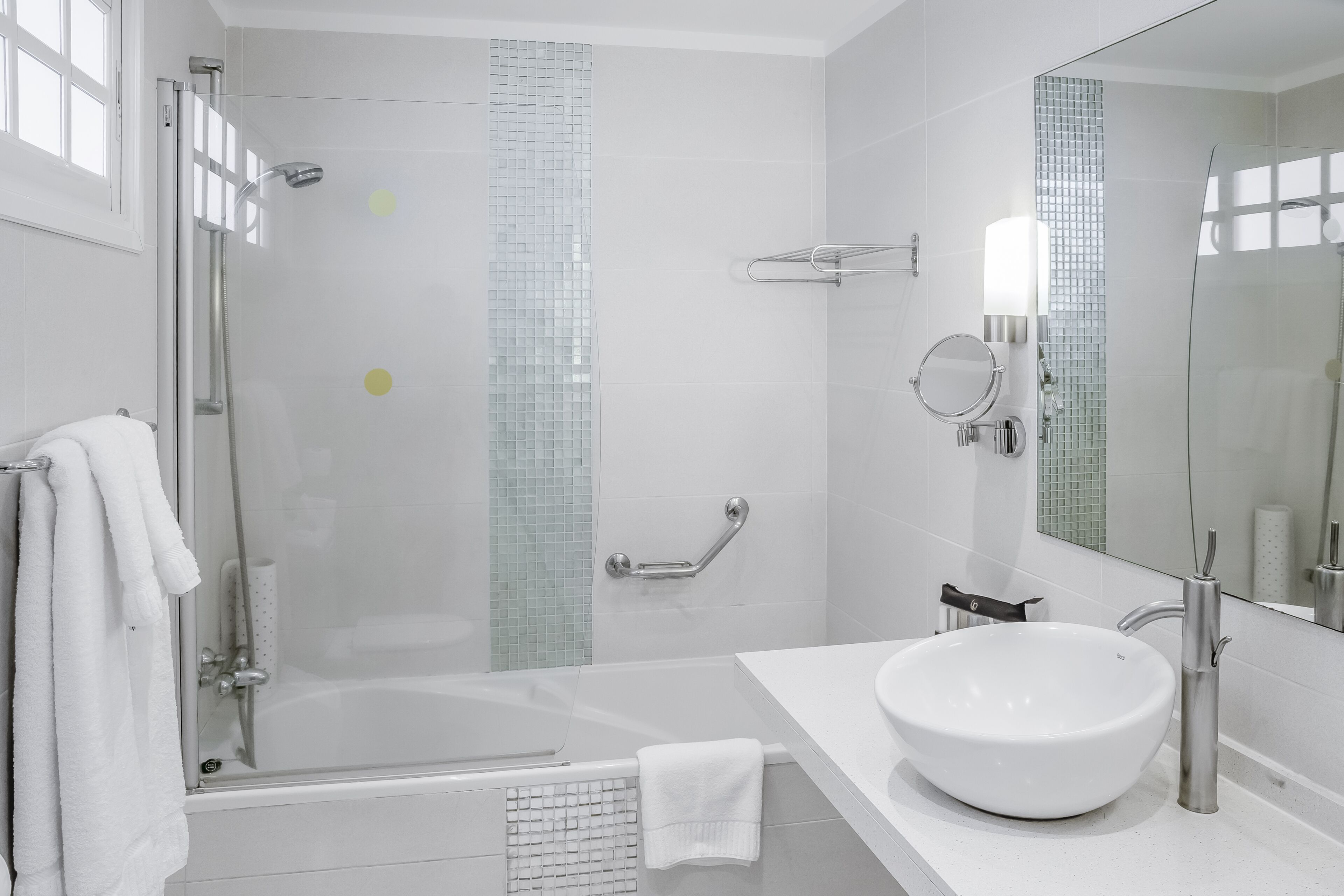 A modern bathroom with a glass-enclosed shower, a white sink, and a large mirror.