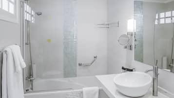 A modern bathroom with a glass-enclosed shower, a white sink, and a large mirror.