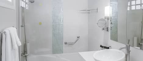 A modern bathroom with a glass-enclosed shower, a white sink, and a large mirror.