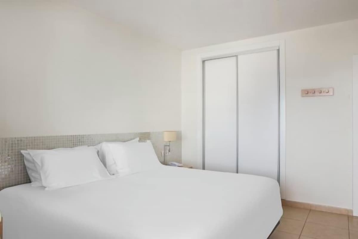 Une chambre d’hôtel avec un lit, une table de chevet, une lampe et une armoire.