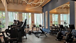 Une salle de sport équipée de tapis de course, de vélos elliptiques et de bancs de musculation.