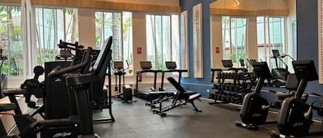 Un gimnasio con cintas de correr, elípticas y bancos de pesas.