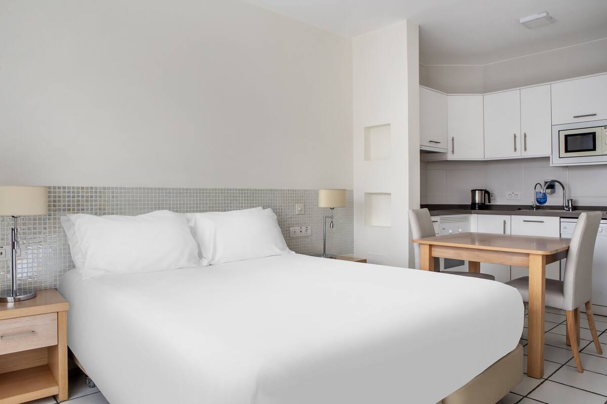 Une chambre d’hôtel comprenant un lit, des tables de chevet, un bureau et une kitchenette.