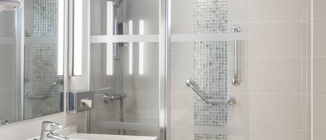 Een moderne badkamer met een douchecabine van glas, een witte wastafel en een spiegel.