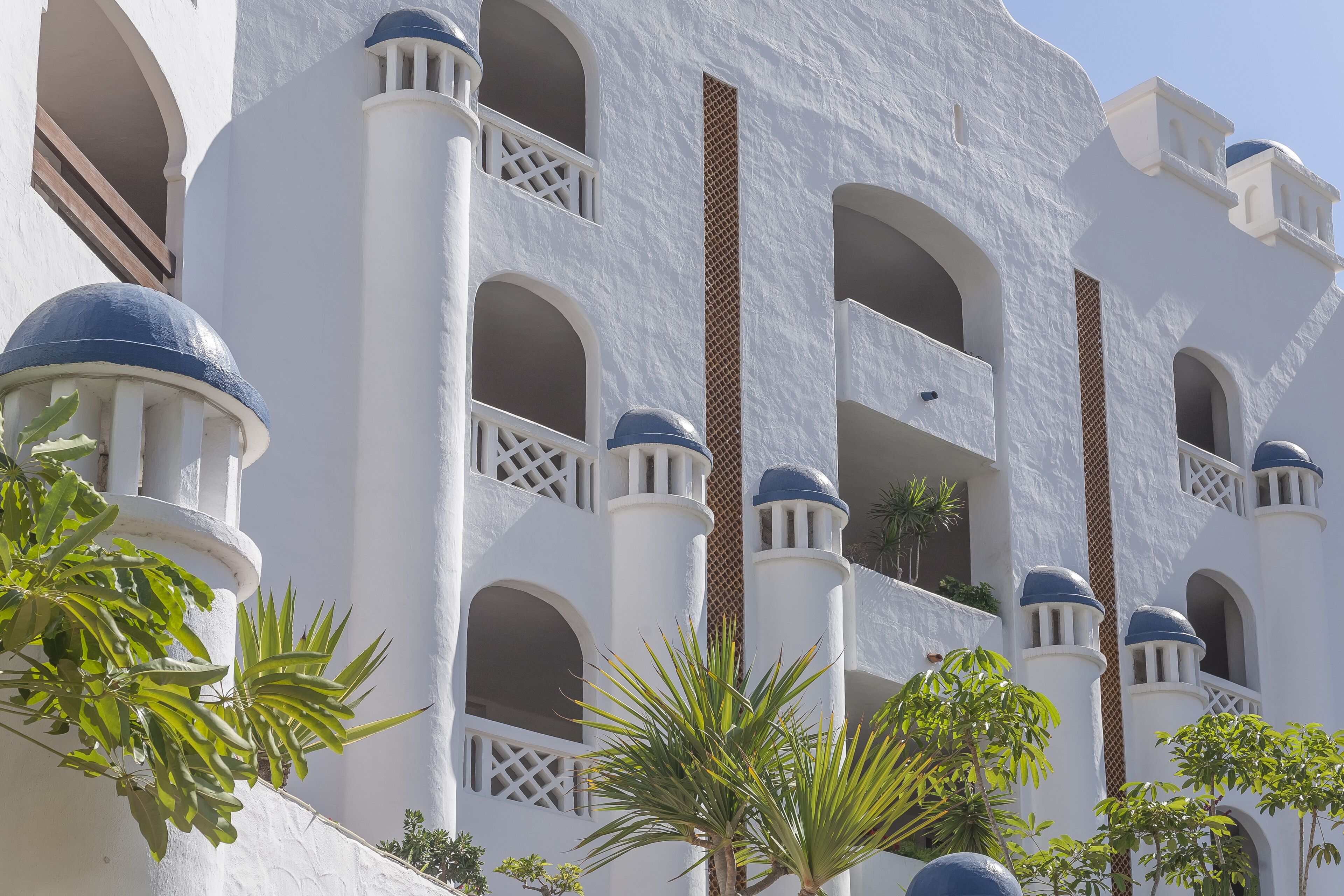 Un edificio blanco con balcones de cúpulas azules y ventanas arqueadas.
