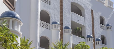 A white building with blue domed balconies and arched windows.