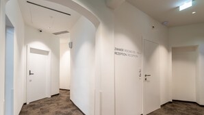 A hallway with a carpeted floor, white walls, and doors labeled "Zimmer | Rooms 105-113 | Reception | Reception." - DaunTown Rooms - Self Check-In (Vienna)